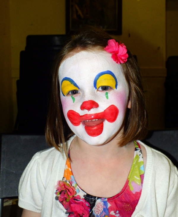clownschminken - ein mädchen sieht lustig aus - mit einer blume in den haaren