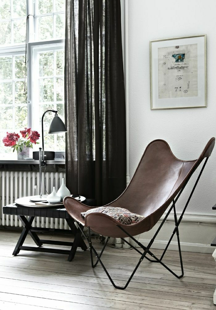 Wohnzimmer-skandinavischer-Stil-Leder-Sessel-industrielle-Leselampe-rote-Blumen-Fenster-durchsichtige-Vorhänge