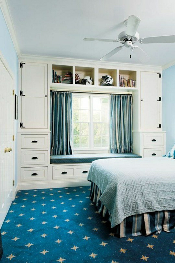 Schlafzimmer-elegante-Gestaltung-blauer-Teppich-Bettwäsche-Gardinen-kleines-Fenszter-weißer-Kleiderschrank