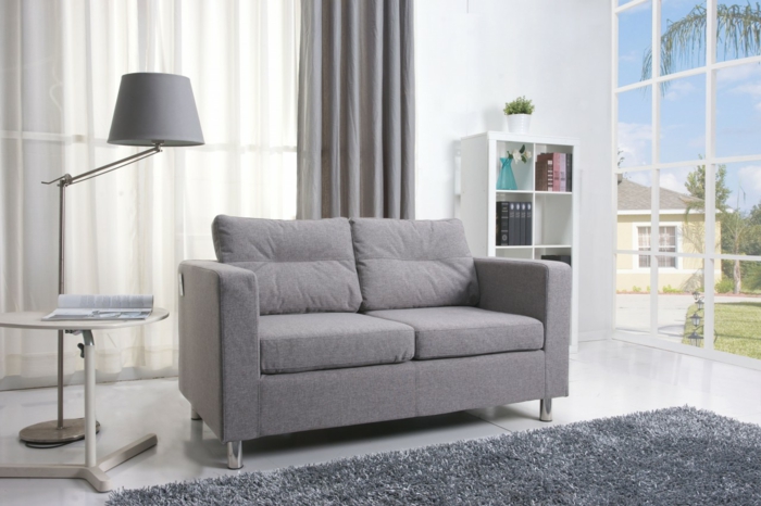 graues-Interieur-kleines-Sofa-Textil-Polster-flaumiger-Teppich-Leselampe-graue-Gardinen