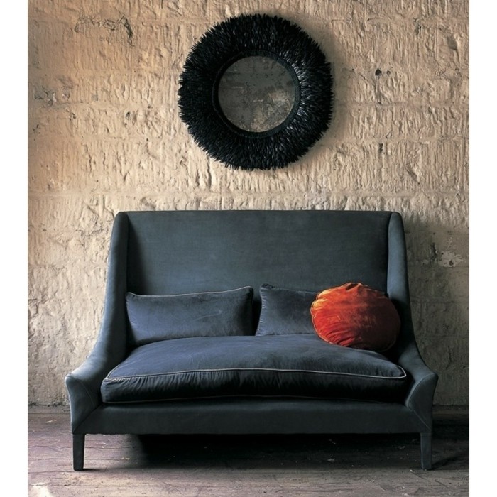 stilvolles-Sofa-dunkelblau-Samt-rundes-orange-Kissen-Wanddekoration-Steinwand