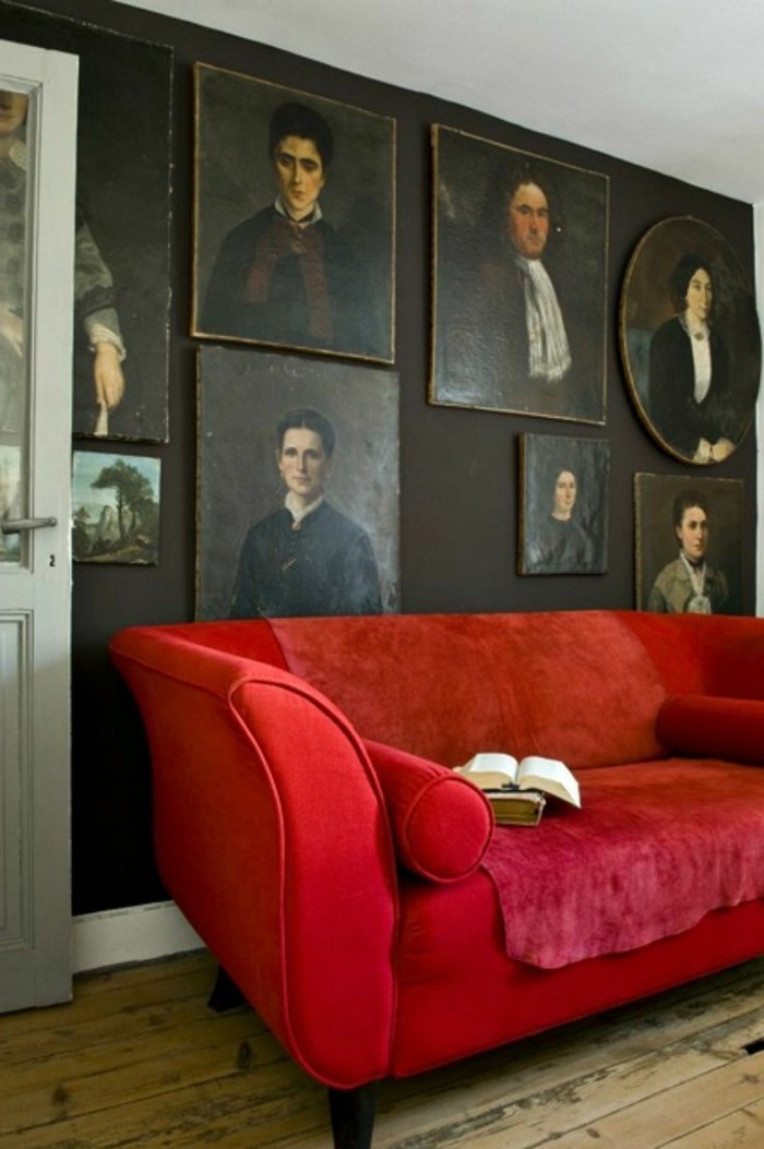 Zimmer-mit-vielen-Portraits-an-der-Wand-Sofa-rot