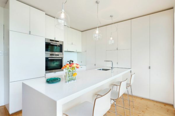 Drei Stühle und gläserne Kronleuchter in einer weißen Küche
