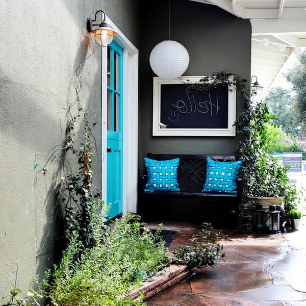 Schwarze Wandtafel und blaue Dekokissen im Eingang des Hauses