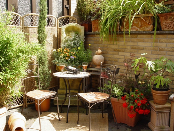terrassengestaltung mit grünen pflanzen, einen runden tisch und zwei stühlen