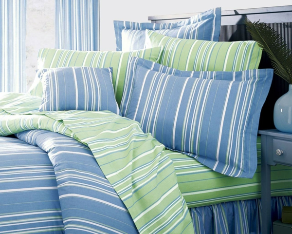 schlafzimmer mit bettwäschen und kissen in blauen weißen und grünen linien