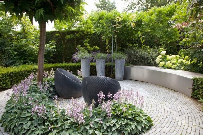 hohe pflanzengefäße in beton optik, gartengestaltung kleine gärten, rosa blumen, runde schwarze stühle