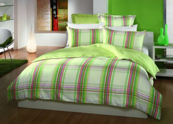 schlafzimmer mit einem bett mit bettwäschen und kissen mit geometrischen linien in grün