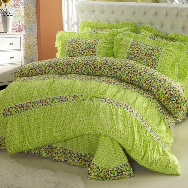 schlafzimmer mit einem bett mit bunten grünen bettbezügen und weißem kopfbrett