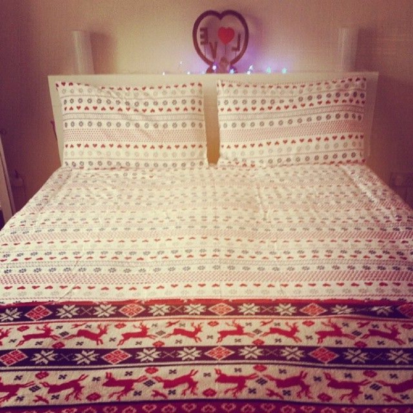 schlafzimmer mit bettwäschen und kissen mit weißer haupfarbe und rosigen linien und geometrischen figuren