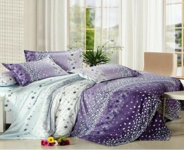 schlafzimmer mit einem bett mit bettbezügen in lila nuancen