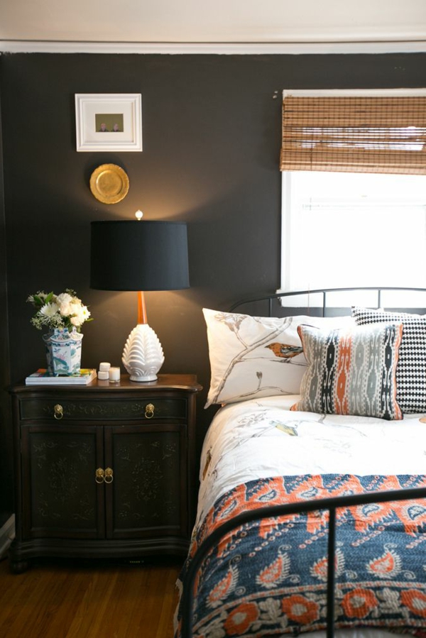 schlafzimmer mit schwarzer wandgestaltung - bett mit weißen und bunten bettwäschen und kissen