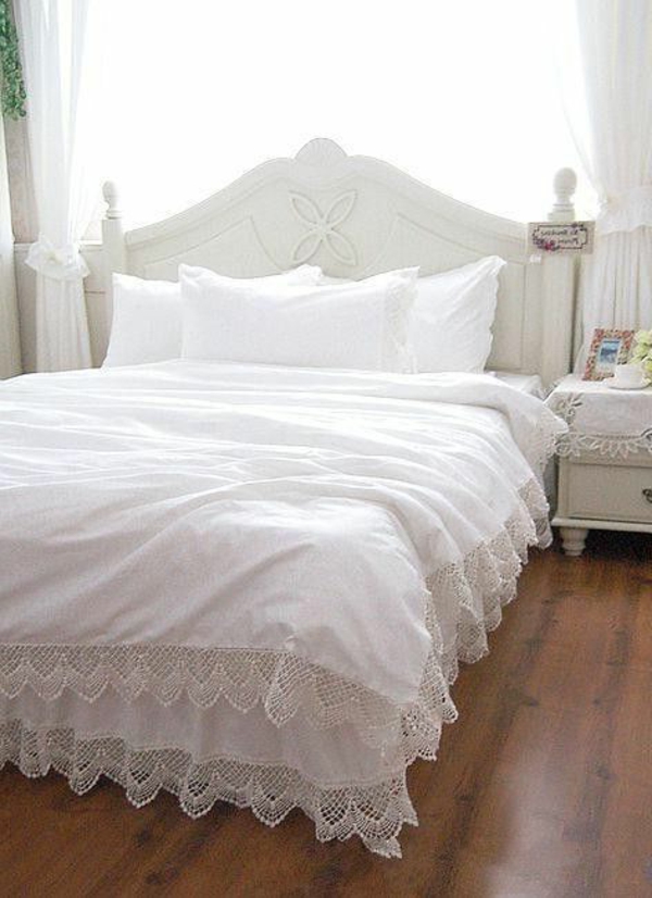 schlafzimmer mit einem bett mit bettbezügen und kissen in weiß
