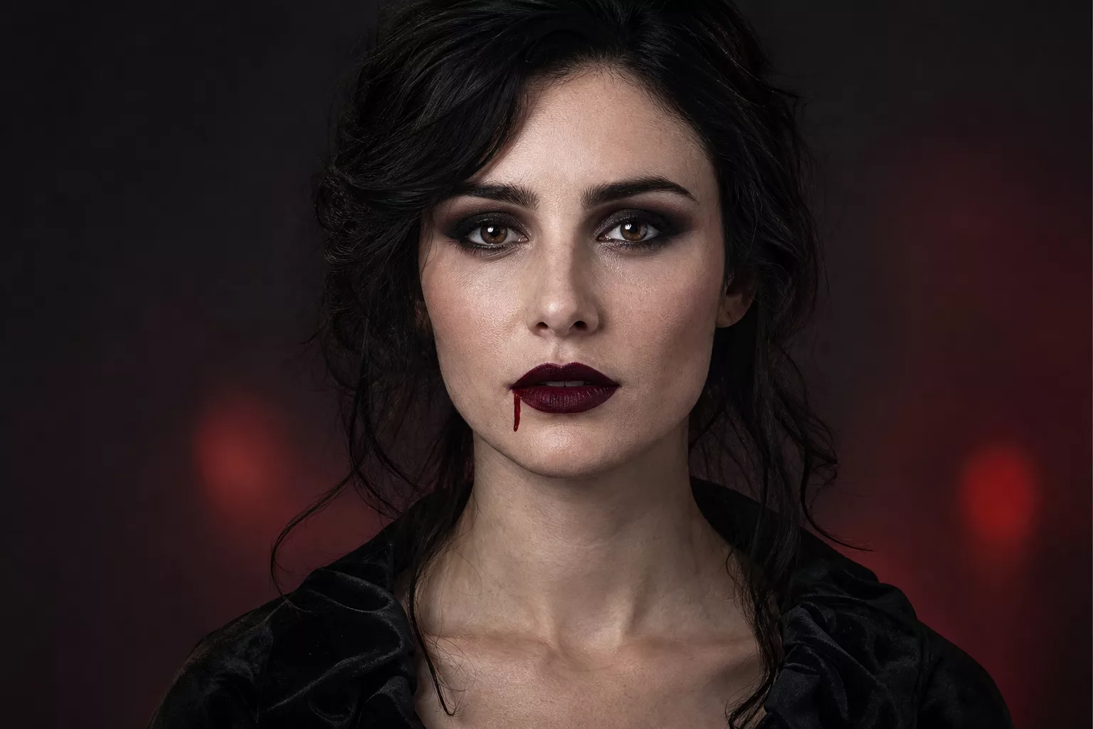 Frau mit dramatischem Halloween Schminken Look, blasse Haut, dunkle Augen