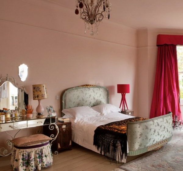 orientalisches schlafzimmer mit einem schönen bett mit einem kopfbrett und gardinen in zyklamenfarbe