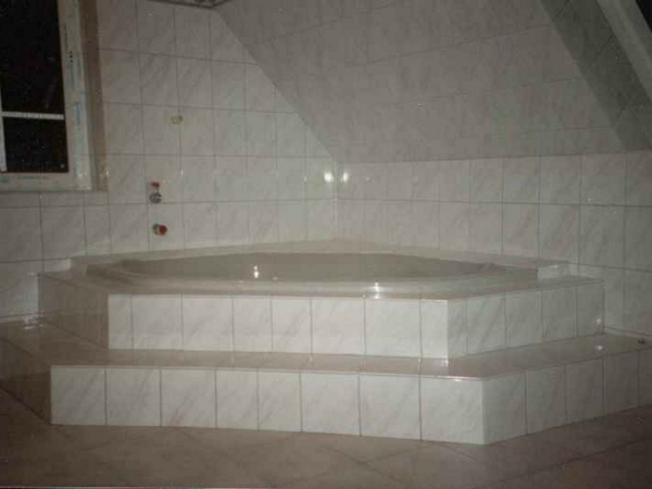 eckbadewanne-einbauen-und-einfliesen-weiße-badfliesen - dachwohnung ausstatten