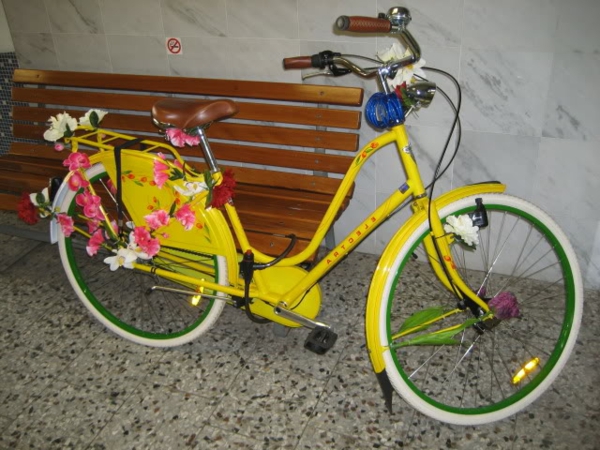 fahrrad-deko-gelb-mit-blumen - eine braune bank daneben