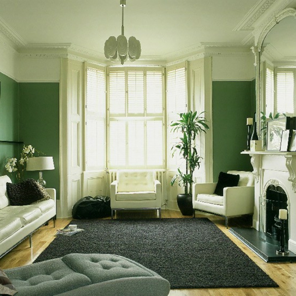 farbgestaltung-wände-grüne-farbtöne - sofa mit dekokissen und ein kamin