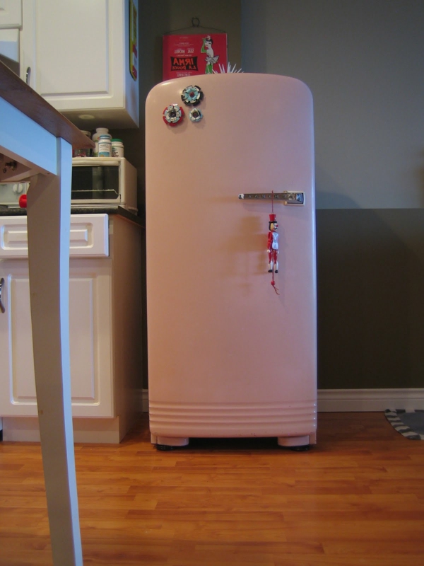 großer-rosa-kühlschrank neben einem weißen schank