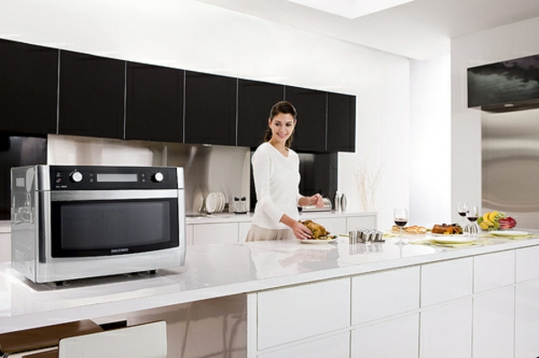 schöne-weiße-küche-samsung-mikrowelle-eine junge und schöne frau kocht