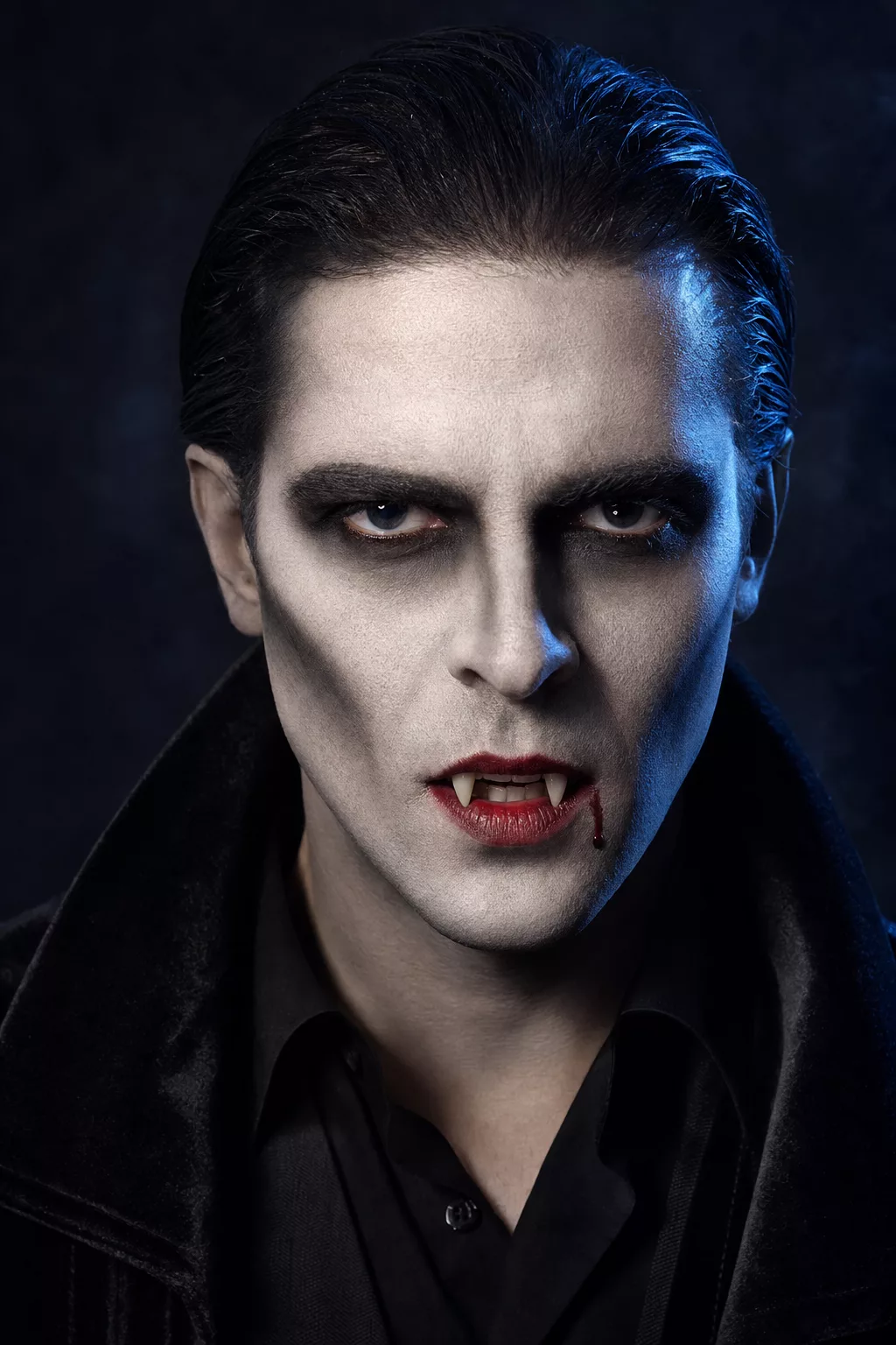 Klassischer Dracula Look: schwarze Kontur, spitze Vampirzähne, blutiger Mundwinkel