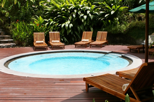 kleiner-runder -pool - umgegeben von liegestühlen und pflanzen
