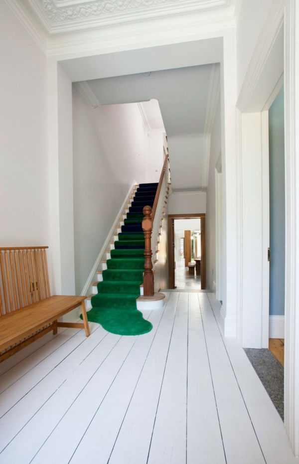 weiße-treppen-und-grüner-teppich im schönen flur mit einer hölzernen bank