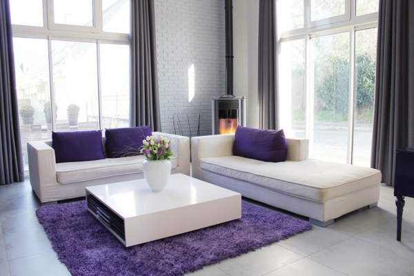 weißes-sofa-mit-sofakissen-in-lila-farbe-gläserne-wände- weicher teppich