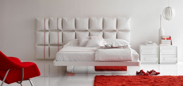 bett-in-weiß-im-schlafzimmer-mit-roten-elementen- dekokissen an der wand