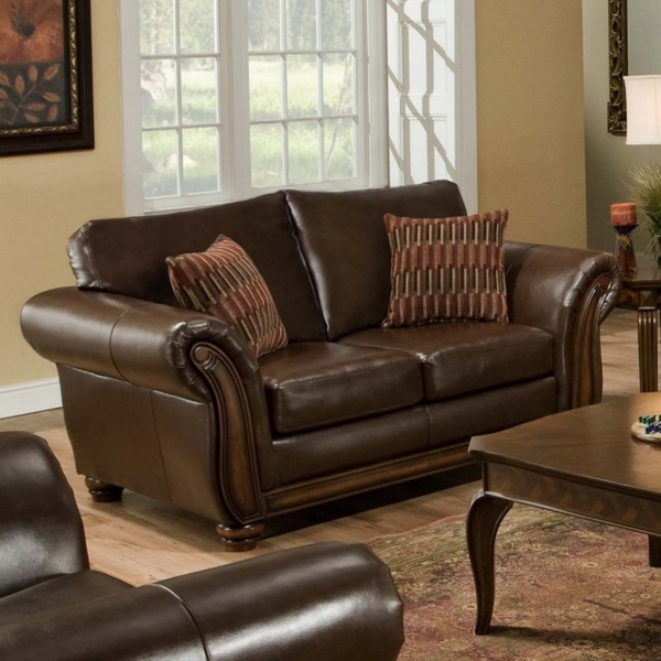 vintage-ledermöbel-eine-couch-mit-braunen-dekokissen- eine glaswand dahinter