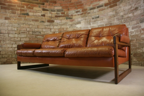 vintage-ledermöbel-sofa-in-braunen-nuancen- eine ziegelwand dahinter