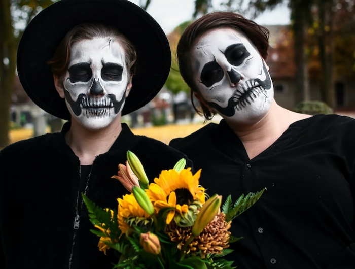 paarkostüme halloween skelette in schwarz mit blumenstrauß im freien