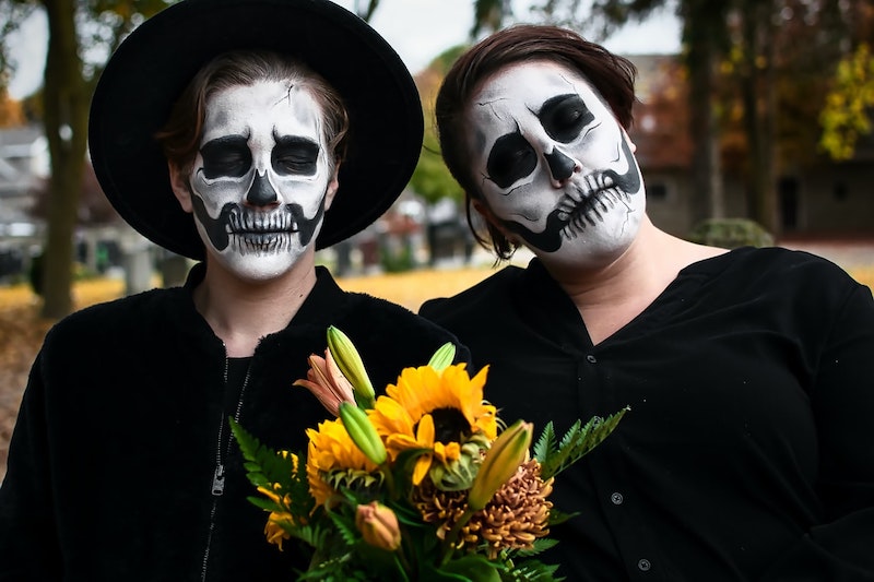 paarkostüme halloween skelette in schwarz mit blumenstrauß im freien