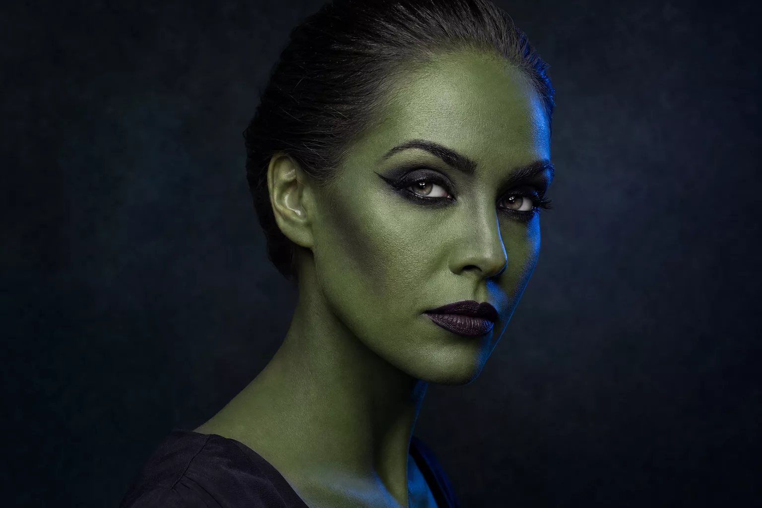 Frau mit klassischem grünem Hexen-Make-up, dunkle Augen, dramatische Kontur