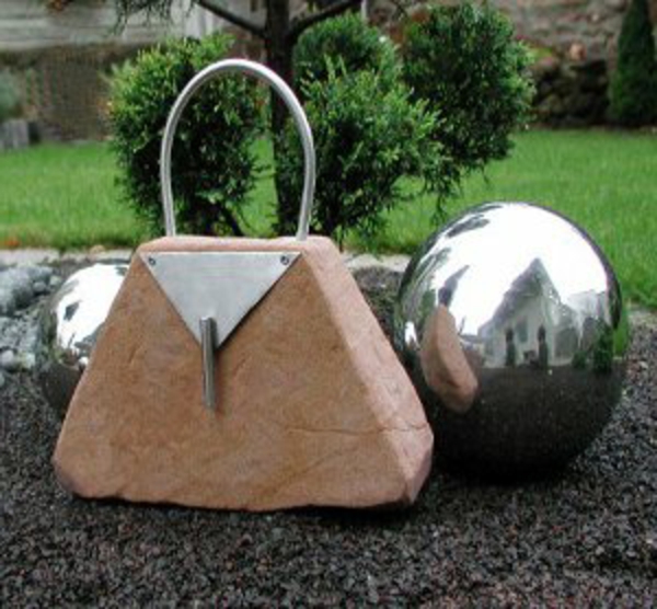 gartendeko-aus-edelstahl-kugel-neben-einer-handtasche-aus-stein