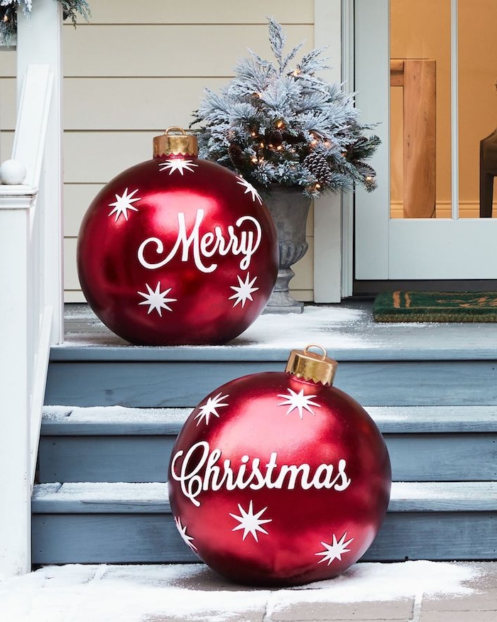 Weihnachtsdeko für den Garten, zwei riesige rote Christbaumkugeln mit weißer Aufschrift Merry Christmas und weißen Sternen 