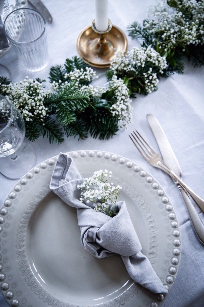 esstisch deko, graue serviette, kleine weiße blüten, immergrüne zweige, festliche weihnachtsdeko