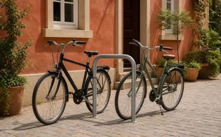 Rahmenhaltender Fahrradständer vor gepflasterter Hofeinfahrt mit zwei Rädern