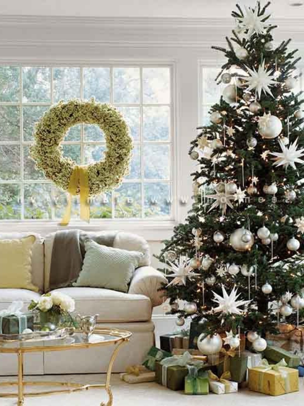 weiße weihnachtsdeko - tannenbaum und ein grüner kranz am fenster
