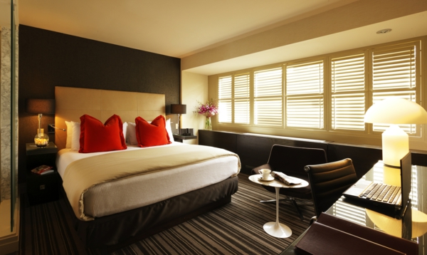 schlafzimmer-design-schicke-jalousien-und-bett-mit-zwei-roten-dekokissen