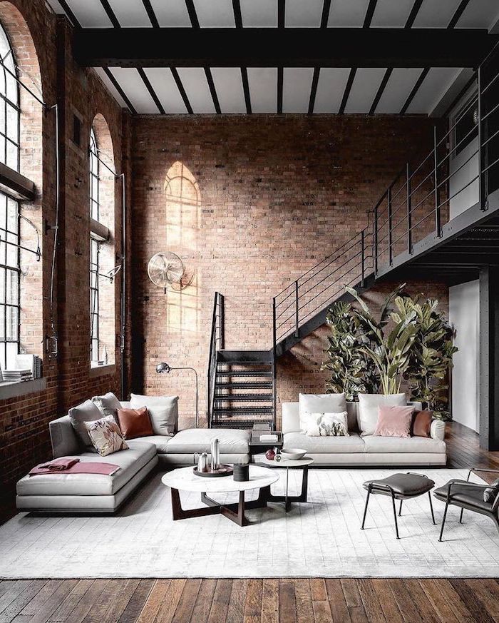 Wohnzimmer Einrichtung in Industrial Stil, nackte Wände, weiße Sofas, runder Couchtisch zweiteilig, Treppe aus Metall