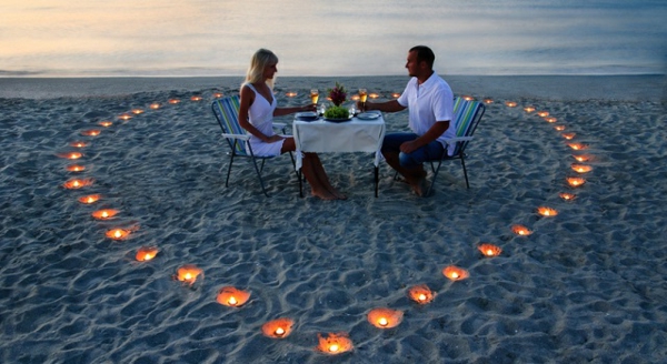 A young lovers couple share a romantic dinner with candles heart