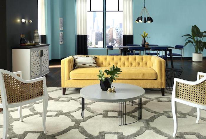 Wohnzimmer in Pastellfarben, gelbes Sofa, runder Couchtisch, Wandfarbe Türkis, Wand in Schwarz 
