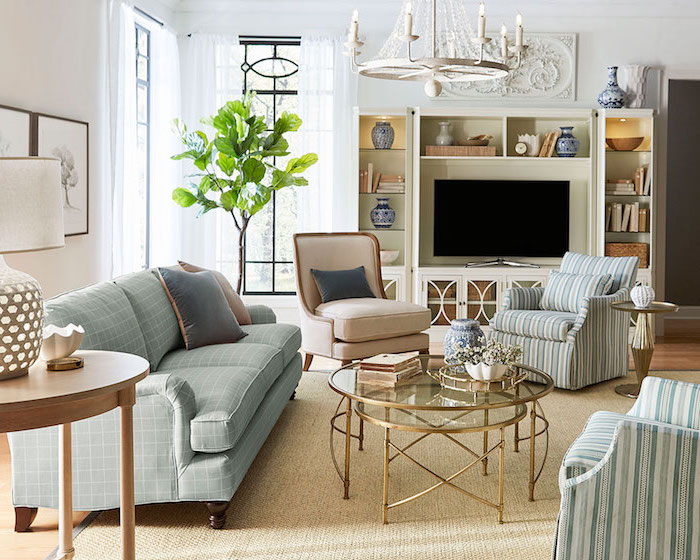 Wohnzimmer Einrichtung in hellen Pastellfarben, kariertes Sofa in Hellblau, gestreifte Sessel, rundes Couchtisch aus Glas und Metall 