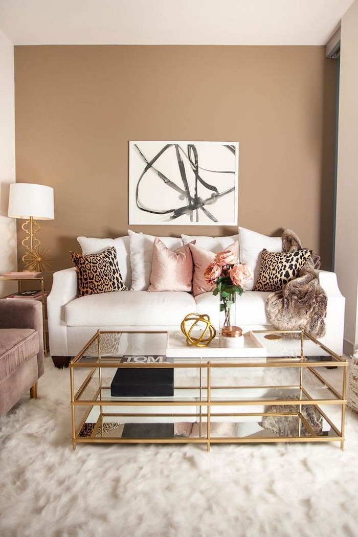 Wohnzimmer in Beige, weißes Sofa, Deko Kissen in Rosa und mit Leopardenprint, Glastisch mit goldenen Kanten 