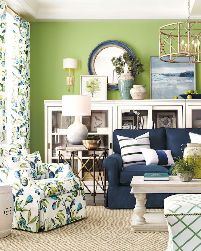 Wohnzimmer in frischen Farben, Wandfarbe Hellgrün, Sessel und Gardinen mit Pflaumen Muster, weiße Schränke und Couchtisch 