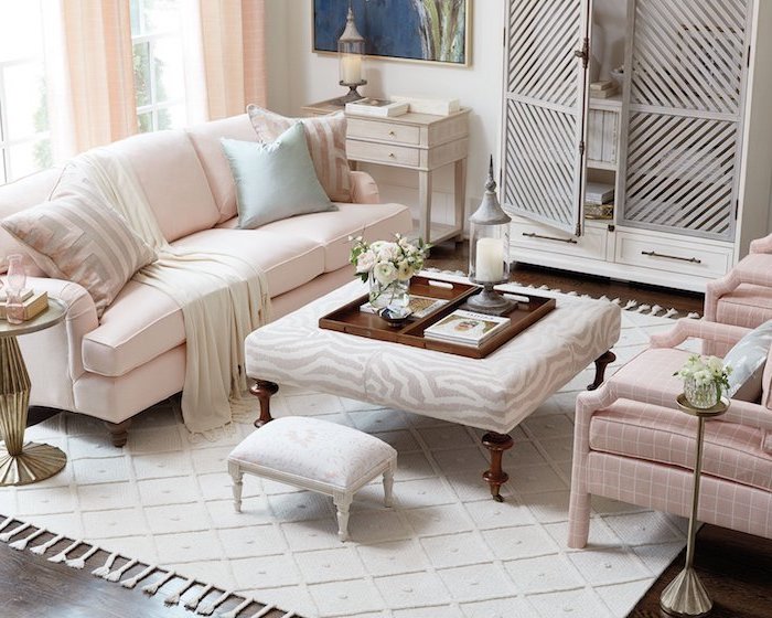 Wohnzimmer in zarten Pastellfarben, Sofa und Sessel in Zartrosa, weißer Teppich, Laterne mit weißer Kerze 