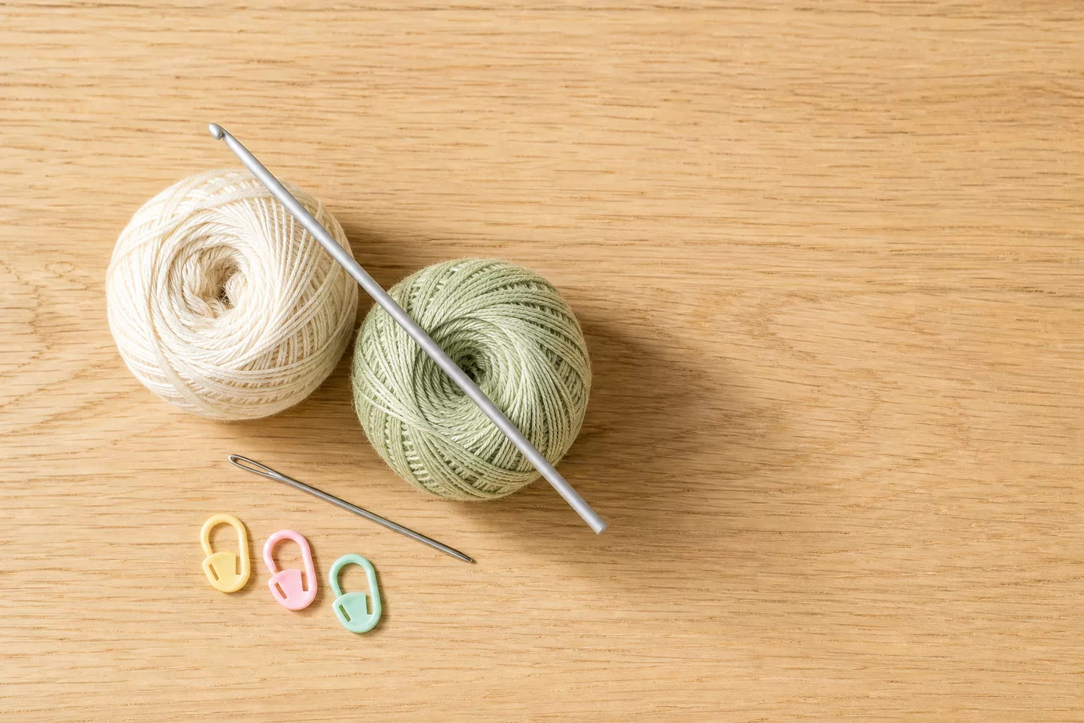 Material-Flatlay für Babyschuhe häkeln mit Garn, Nadel und Wollnadel
