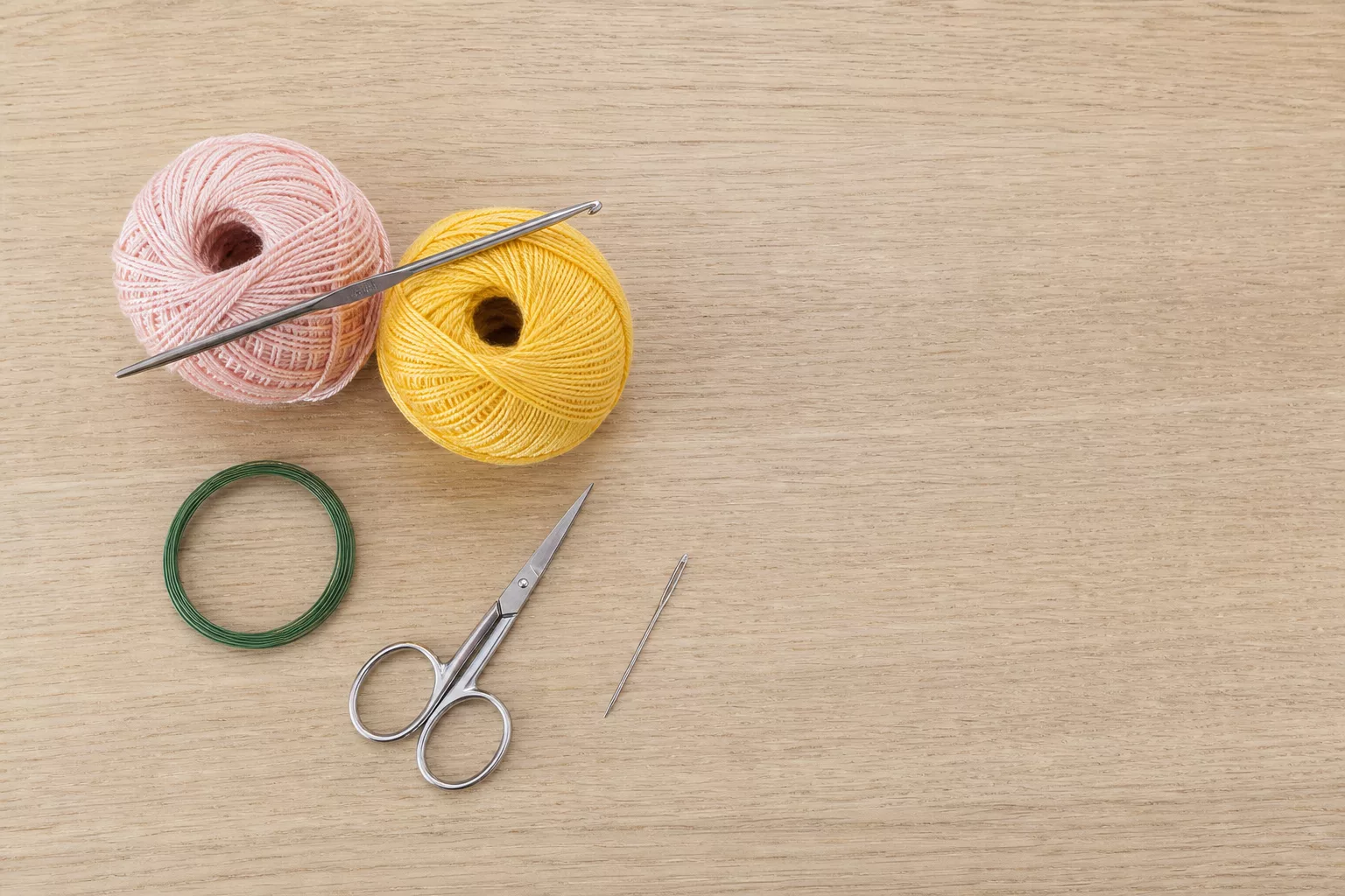 Material-Flatlay für Häkelblumen mit Baumwollgarn, Nadel und Draht