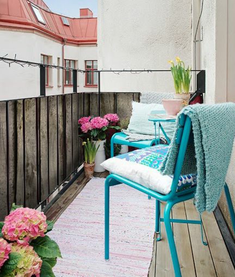 balkon-bepflanzen-blauer-stuhl-rosige-blumen